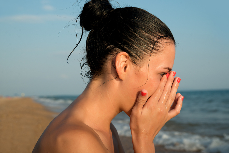 woman rubbing her eyes at the beach