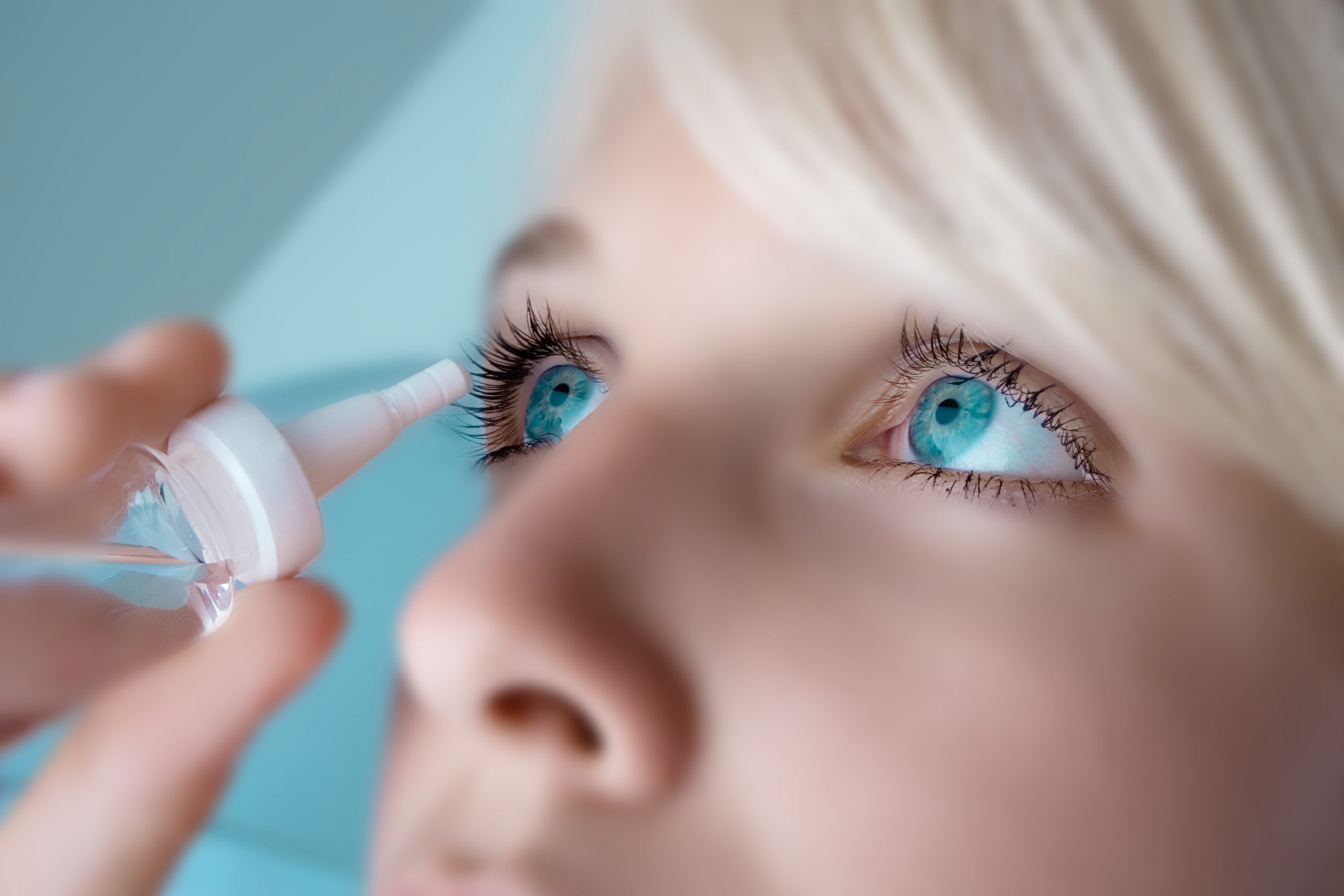 woman applying eyedroppers, close up