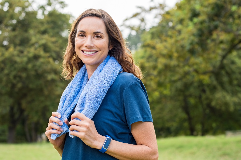 Happy mature woman smiling at park after exercise. Portrait of m