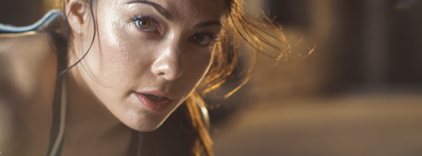 Close-up Shot of a Beautiful Athletic Woman Looks into Camera. She's Tired after Intensive Cross Fitness Exercise.