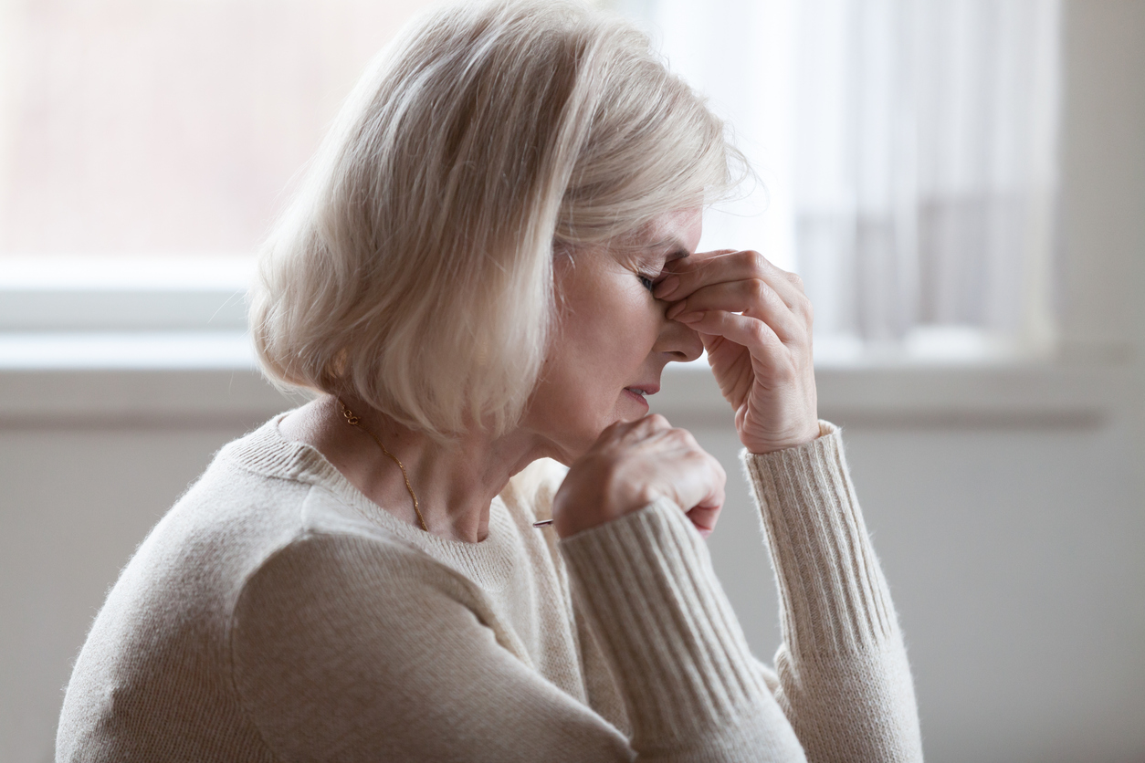 Older woman holding her eyes, struggling with vision loss. Deciding on iLasik in Orange County.