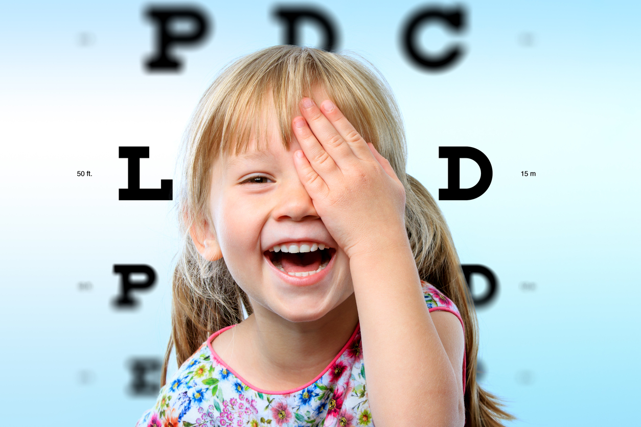 Happy little girl at children's eye care office doing a vision test