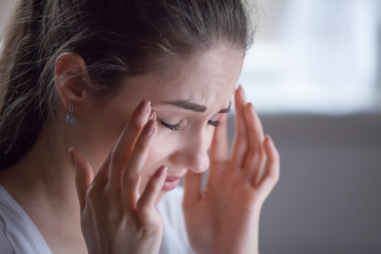 Young woman rubbing eyes wondering why does LASIK cause dry eye