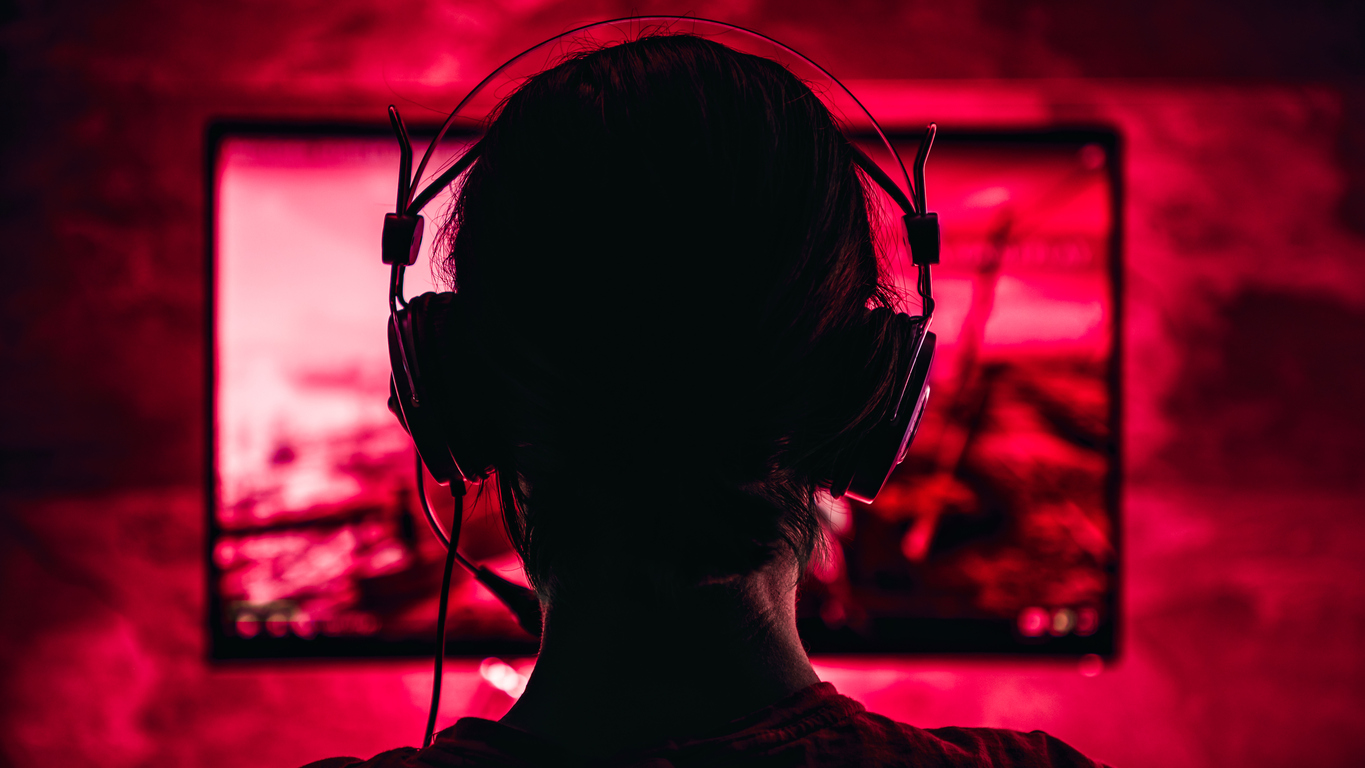 Boy with headphones on looking at red video game screen