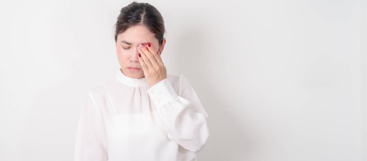 Woman touching eye in discomfort.